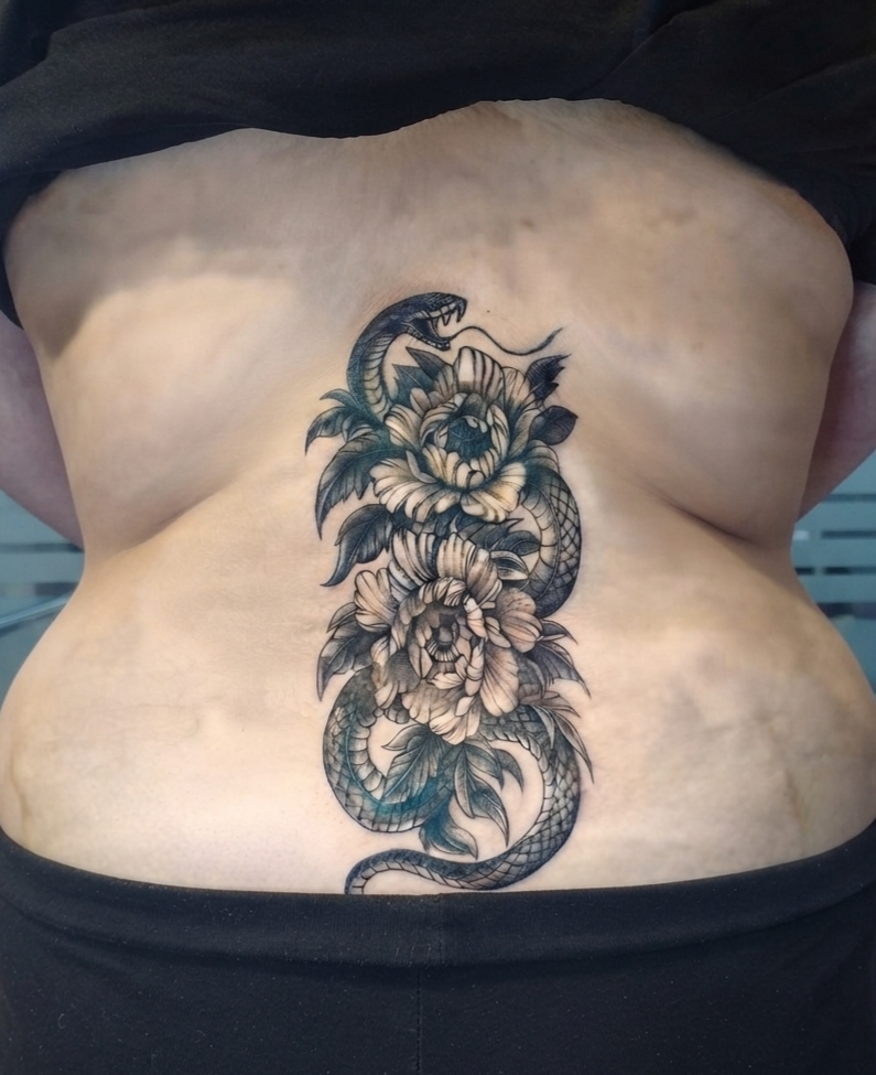Tatuaje floral con serpiente en blanco y negro, espalda baja